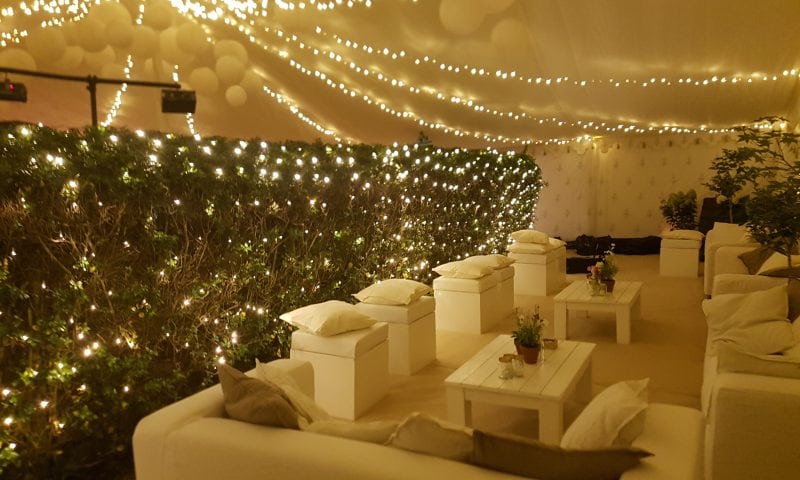 Bar area with cascade fairy lights behind the counter, a bartender and bottles on display