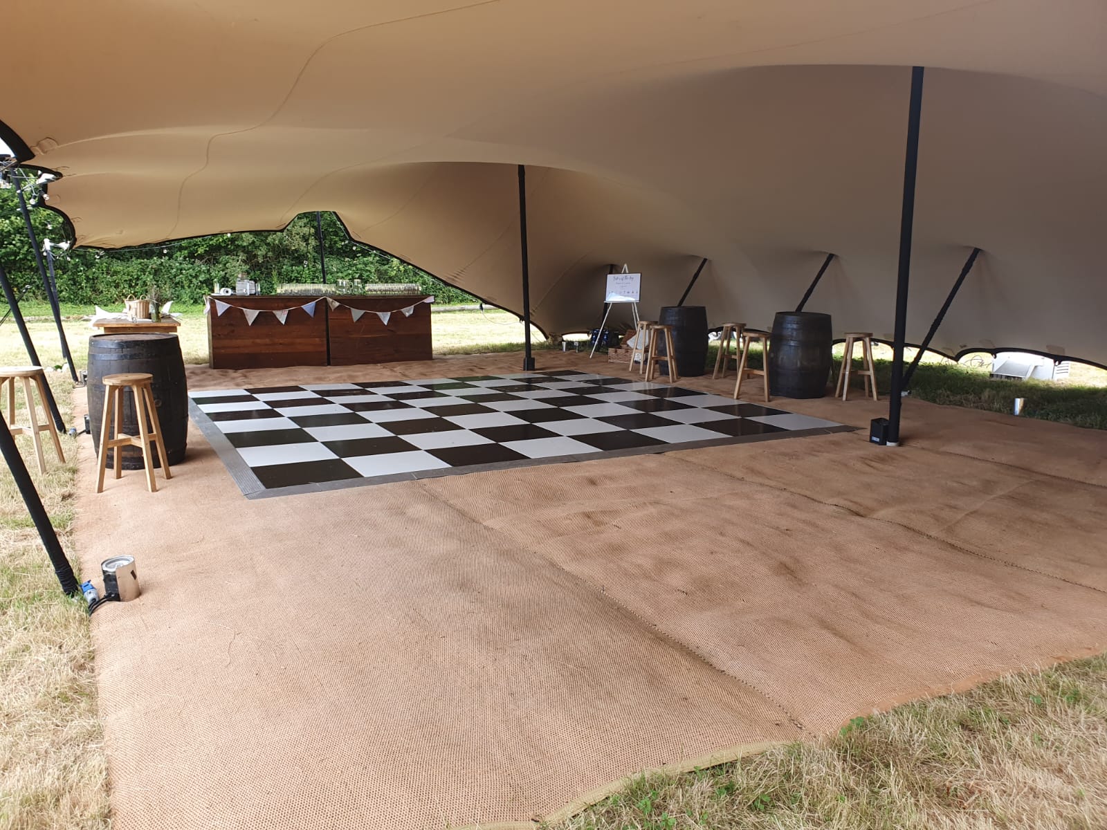 Open canopy interior with dance floor, wooden bar and simple furniture on a timber floor