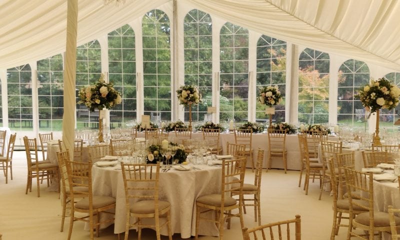 Interior of a clearspan marquee for an autumn wedding — Gothic arched windows, pale grey linen, gold candelabra