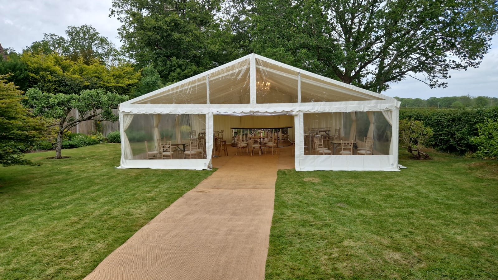 White clearspan marquee viewed from the front — a walkway leads into a fully dressed dining area