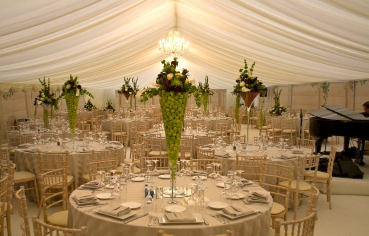 Interior of a clear-span marquee dressed for an elegant wedding with chandelier and gold chiavari chairs