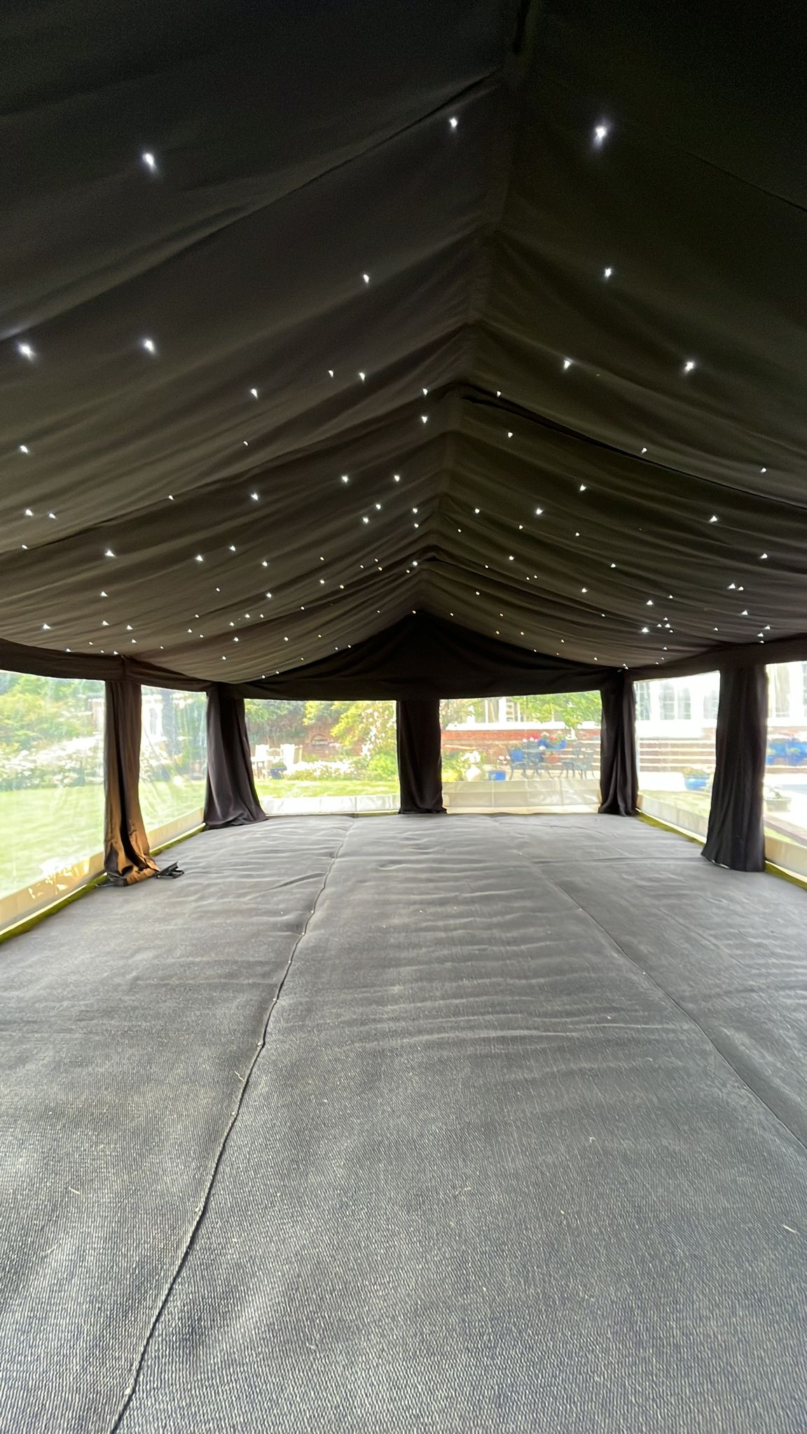 Long empty marquee interior with starcloth-style dark ceiling and small ceiling lights over a plain floor