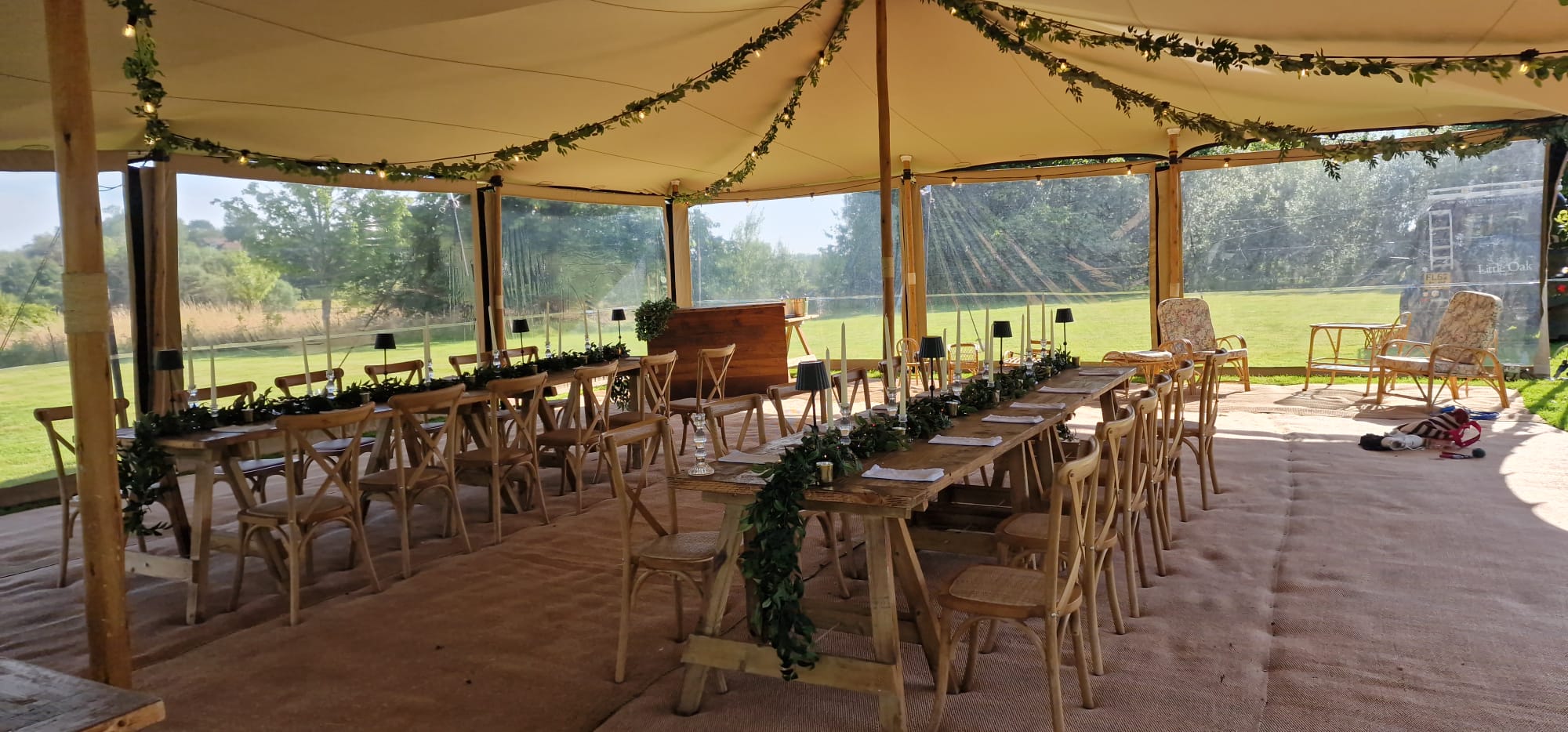 Wide open-sided dining marquee with long rows of tables, natural light and countryside views