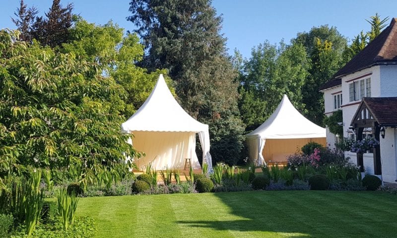 Two white pagoda marquees linked together in a beautiful English garden with flowering borders