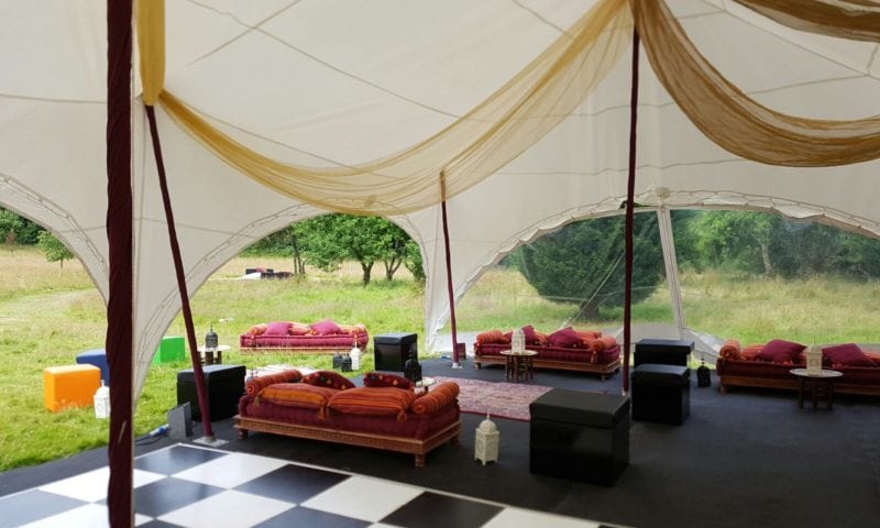 Pagoda marquee interior with white and gold ceiling draping, exotic red velvet Indian daybeds and a chequered dance floor