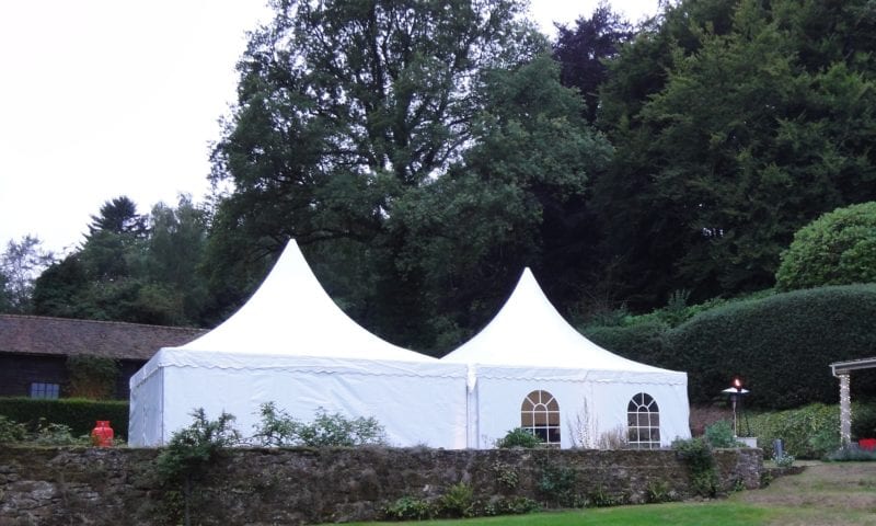 Two white pagodas linked together in a pastoral English country garden at dusk with a flame torch visible