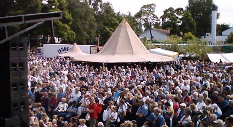 A large crowd at an outdoor festival or agricultural show, with a single large tipi visible — demonstrating capacity