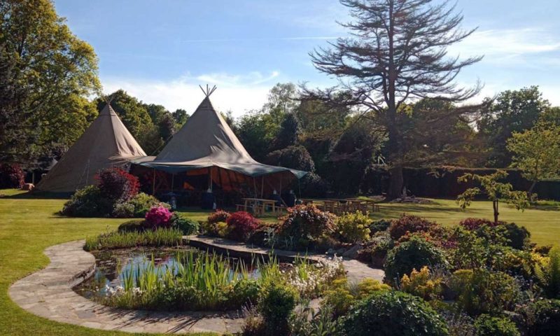 Double tipi in a stunning English private garden with ornamental pond and azalea in full flower