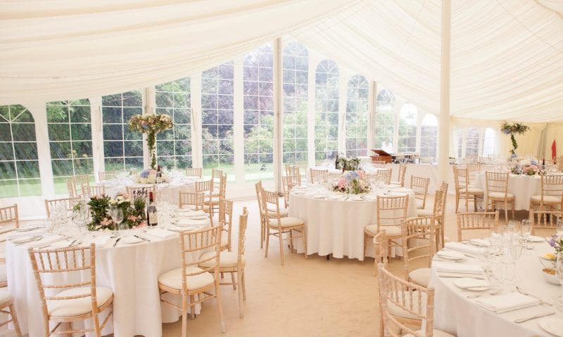 Traditional marquee interior with large Georgian arched windows revealing a beautiful garden beyond