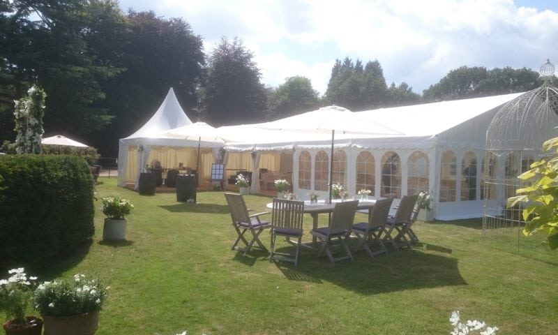 Exterior of a traditional marquee and linked pagoda in a beautiful English garden on a sunny day