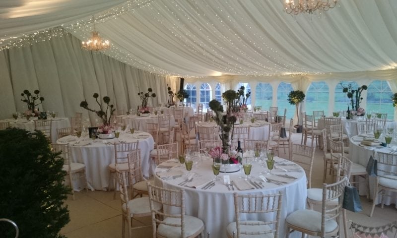 Interior of a traditional marquee for a winter wedding — chiavari chairs, pink thistle centrepieces and chandelier