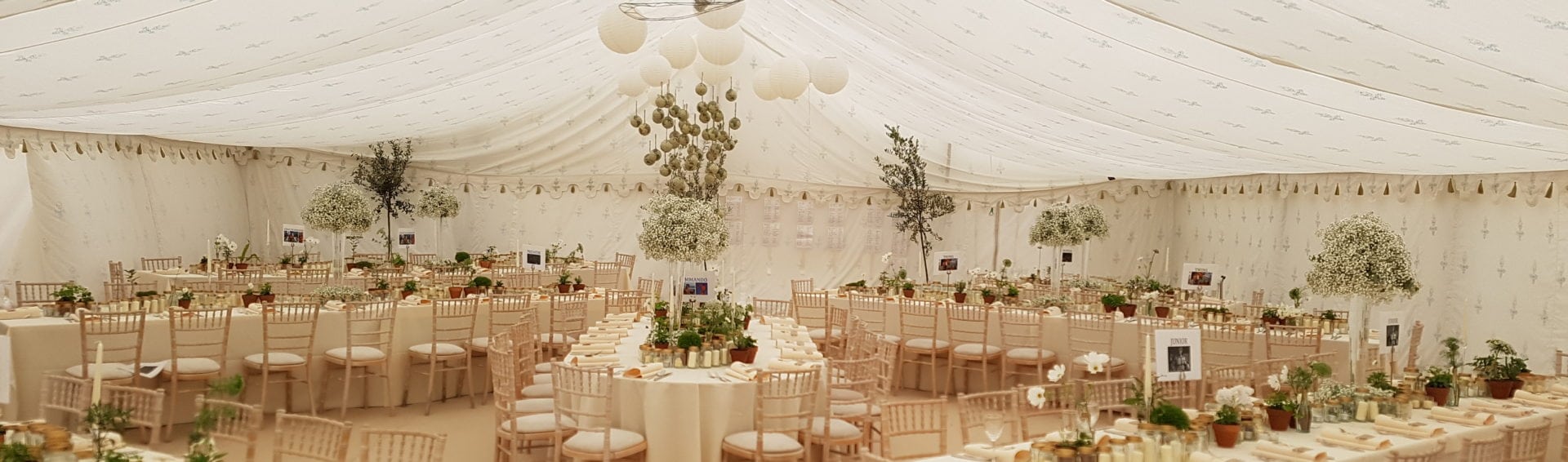A wedding marquee interior with Indian fleur-de-lis lining, tall centrepieces and gold chiavari chairs
