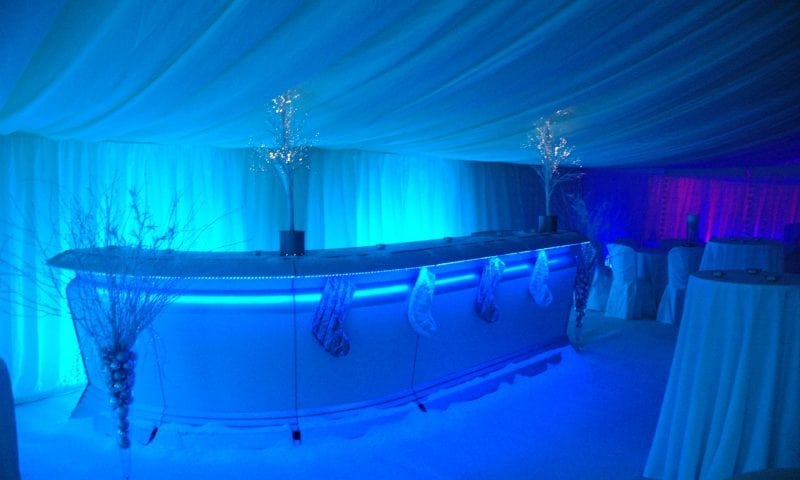 Corporate marquee at night with electric blue uplighting, illuminated bar and crystal-lit bare branch trees — Winter Wonderland